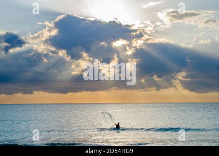 Miami Beach Florida,Atlantic Ocean surf,casting tossing fishing net,water man male silhouette silhouetted,clouds,