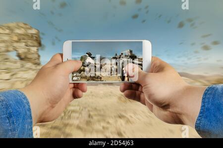 First person view photo of a male hand in jeans shirt holding smartphone and taking photo in forest. Stock Photo