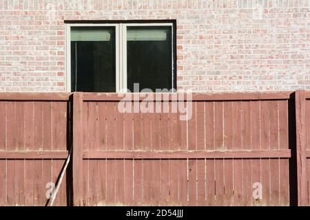 Textured background of brown weathered wooden fence and brick wall with open window with blinds Stock Photo