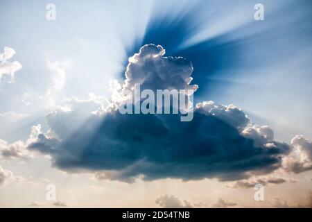 A muscular cloud with the rays of the sun peeping out from behind him Stock Photo
