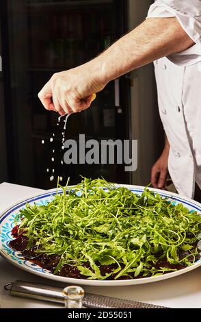 Beet carpaccio. Chef pours lemon on beetroot carpaccio with sauce and herbs. Stock Photo