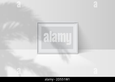 Tropical palm leaf shadow falls on blank horizontal white picture frame Stock Vector