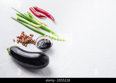 Baked aubergine ingredients, for cooking or grill chili pepper, eggplant, sauce, nuts on white background side view space for text. Stock Photo
