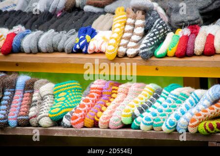 handmade multi-colored knitted socks and slippers lie on the window of a street market Stock Photo