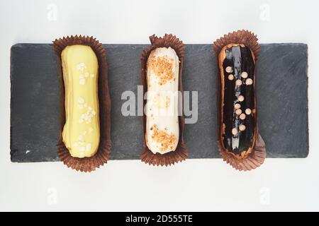 Three eclairs on a black tray top view Stock Photo