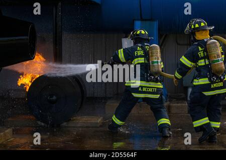 New Jersey state fire protection specialists Adam Beckett, left, and Dave Amodio with the New Jersey Air National Guard's 177th Fighter Wing extinguish a simulated aircraft wheel fire during live fire training at the Aircraft Rescue and Fire Fighting Training Center, Philadelphia International Airport, Pa., Sept. 15, 2020. The Atlantic City Air National Guard Base firefighters perform aircraft live fire training twice a year. The state-of-the-art facility is equipped with a simulator, which allows for interior and exterior training and includes a multitude of various fire scenarios, and an air Stock Photo