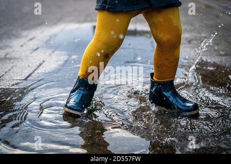 October 7th, 2020, Trebbin, a little girl with rubber shoes and yellow tights jumps around in a puddle and has a lot of fun. | usage worldwide Stock Photo