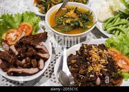 Close up Sweet leaf soup (Star gooseberry) with roasted fish ,Battered fried pork and Larb (Spicy minced pork salad) and Stir fry Katurai chili Stock Photo