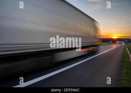 truck speeding up on the highway going towards the setting sun Stock Photo