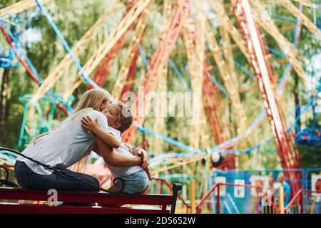 Embracing each other. Cheerful little girl her mother have a good time in the park together near attractions Stock Photo