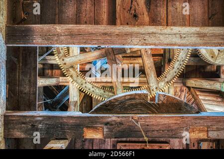 Wooden beam supports wooden cog and gears in an old windmill for wheat grinding. Old technology gearwheel in a rural wind mill in a wooden interior Stock Photo