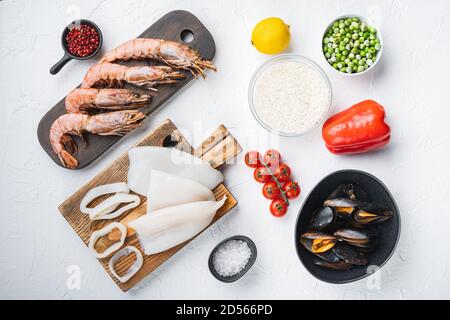 Fresh uncooked sea food specialties and rice for spanish paella on white textured background, flat lay Stock Photo