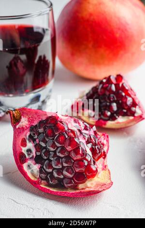 Pomegranate cut with seeds close up in front of garnet cut and juice in glass side view, on white background, selective focus Stock Photo