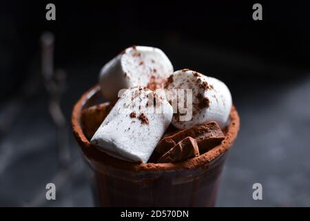 Hot chocolate and marshmallows. Cocoa in a glass goblet, cup. Dark background. Closeup. Stock Photo