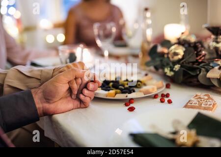 Close-up of hands holding together at the table at Christmas, praying concept. Stock Photo