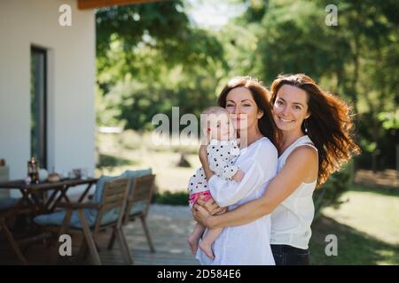 Woman with daughter and baby granddaughter resting outdoors in backyard. Stock Photo