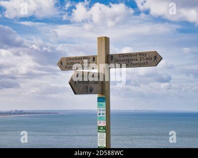 With Redcar in the distance, a wooden signpost on the Cleveland Way national trail near Saltburn in the north east of the UK Stock Photo