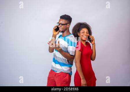 two young black people making phone calls, standing against a white background Stock Photo