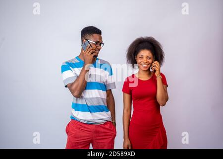 two young african people making phone calls, standing against a white background Stock Photo