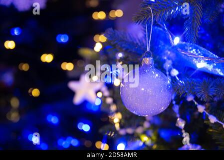 White ball hanging on a Christmas tree, Christmas ornaments at night, blue and gold holiday lights Stock Photo