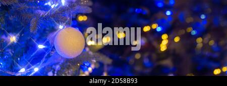 White ball hanging on a Christmas tree, Christmas ornaments at night, blue and gold holiday lights panoramic background Stock Photo