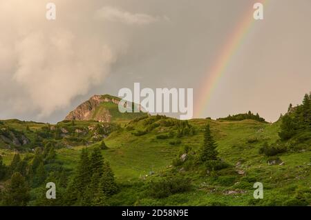 Rainbow in the Austrian alps. Rainbow above a mountain peak in the mountains. Rainbow in the alp mountains. Stock Photo
