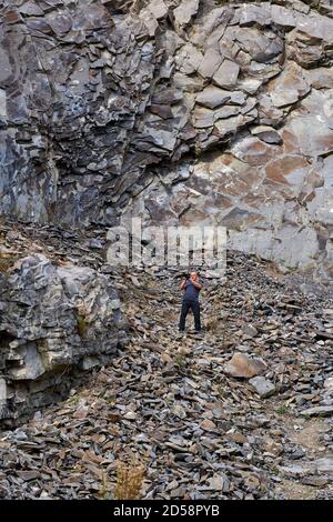 Professional photographer documenting various rock types in an abandoned ancient quarry Stock Photo