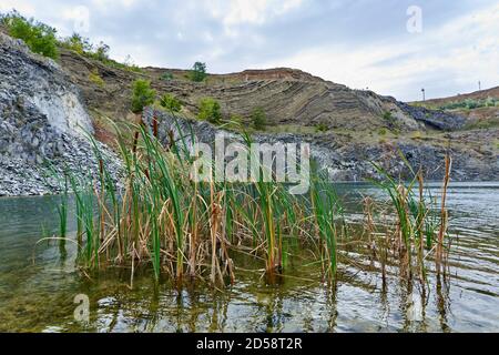 Landscape with a lake formed in an ancient quarry with sedimentary rocks and geological layers visible Stock Photo