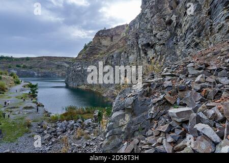Landscape with a lake formed in an ancient quarry with sedimentary rocks and geological layers visible Stock Photo