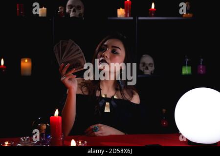 Asian woman get rich from fortune telling business. Fortune teller holding money. Stock Photo