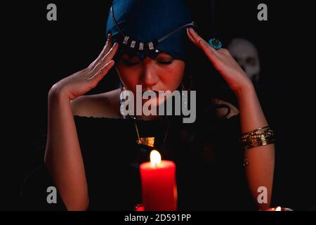 Fortune teller casting spell over red candle during forecasting future. Stock Photo