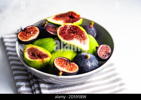 Bowl of green and purple figs  on a folded tea towel Stock Photo
