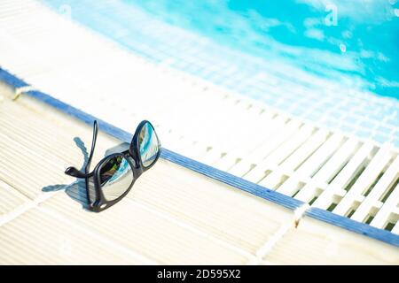 Sunglasses lying on the ground next to a swimming pool
