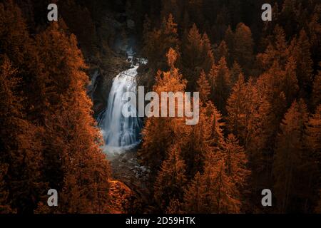 Waterfall surrounded by orange coloured larch trees in fall, Salzburg, Austria Stock Photo