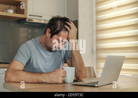 Disappointed freelancer at home office having job problems with his head in hands, selective focus Stock Photo