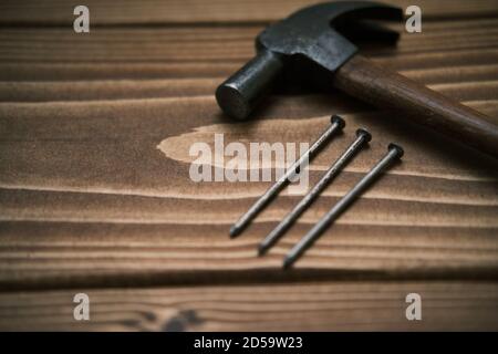 Close up view of a hammer with nails on a wooden table Stock Photo