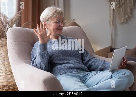 senior woman using tablet sitting at home chatting with friends Stock Photo