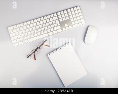 Top view of white office desk table with computer keyboard, glasses and mouse Stock Photo