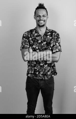 Happy young bearded handsome African man against gray background Stock Photo