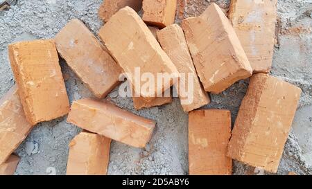 Directly above terracotta bricks scattered on dusty cement ground. Cracked red clay bricks closeup Stock Photo