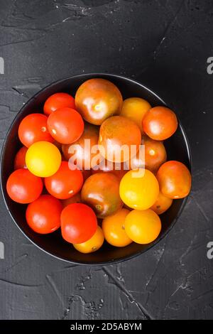 Cherry tomatoes in bowl on black background top view. Stock Photo