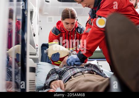 Selective focus of paramedics in uniform doing cardiopulmonary resuscitation to man during first aid Stock Photo