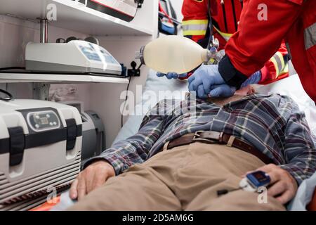 Selective focus of paramedics doing cardiopulmonary resuscitation to patient with heart rate monitor in ambulance car Stock Photo