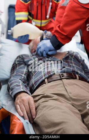 Selective focus of senior man lying in ambulance car near paramedics doing cardiopulmonary resuscitation Stock Photo
