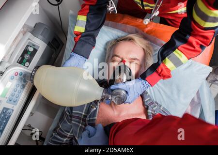 Top view of paramedics in latex gloves doing cardiopulmonary resuscitation to senior man Stock Photo