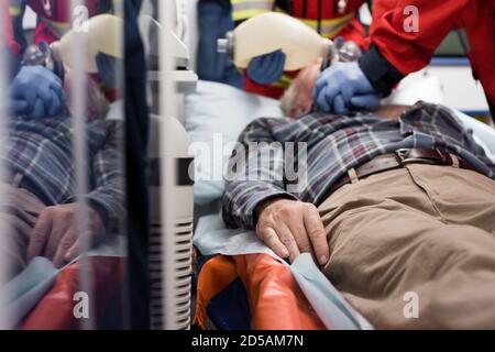 Selective focus of elderly patient lying in ambulance car while paramedics doing cardiopulmonary resuscitation Stock Photo