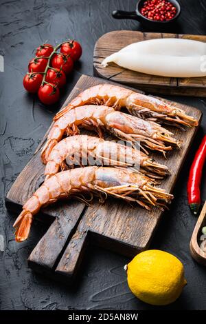 Set of king shrimps with ingredients for paella on black textured background Stock Photo