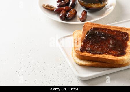 Fresh toasts with dates jam without sugar on white table. Close up. Copy space. Stock Photo