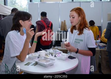 At the canteen. Two girls, employees, standing at the table with empty plates and communicating during lunch. October 2, 2020. Kyiv, Ukraine Stock Photo