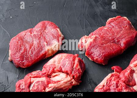 Two raw organic rump beef steaks, side view on black textured table. Stock Photo